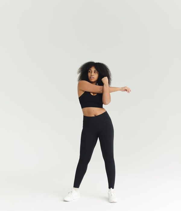 Woman in activewear performing a dynamic cardio movement in a minimalist studio.